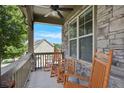 Cozy front porch featuring stone accents, rocking chairs, and a ceiling fan, perfect for relaxation at 218 Ballymore Lane Ln, Acworth, GA 30102