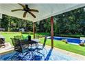 Outdoor patio featuring dining table and chairs, ceiling fan, hammock, and pool in a lush backyard at 2068 Tribble View Way, Lawrenceville, GA 30045