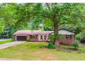 Inviting single-story home with brick exterior, a well-maintained lawn, and mature trees providing ample shade at 3156 Laurel Way, Snellville, GA 30078
