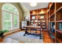 Bright office space featuring custom wood built-ins, a large window with shutters and hard wood flooring at 121 Fairway Overlook, Woodstock, GA 30188