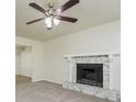 Cozy living room featuring a stone fireplace, neutral carpet, and a ceiling fan at 5107 Rails Way, Norcross, GA 30071