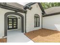 Arched entry to a white brick home with black trim and modern glass doors at 6394 Wood Valley Rd, Douglasville, GA 30134