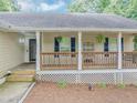 Close-up of a welcoming covered front porch with a wooden railing and decorative shutters at 250 Daileys Plantation Dr, Mcdonough, GA 30253