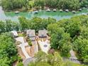 Aerial view of a lakeside property with a circular driveway, green space, mature trees, and lake access at 6900 Driskell Cir, Cumming, GA 30041