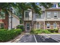Attractive townhome featuring a stone facade, manicured landscaping, and designated parking space at 1244 Harris Commons Pl, Roswell, GA 30076