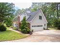 View of attached two-car garage with an automatic door plus manicured lawn and beautiful plantings at 1587 Red Fox Sw Run, Lilburn, GA 30047
