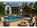 Inviting backyard features a pool, fire pit, covered patio with fireplace, and manicured landscaping at 10745 Shallowford Rd, Roswell, GA 30075