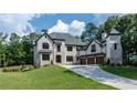 Stunning white brick home on a manicured lawn, showcasing architectural details and a three-car garage at 10745 Shallowford Rd, Roswell, GA 30075