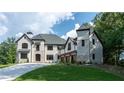 Elegant white brick home with a modern design, featuring a three-car garage and lush green lawn at 10745 Shallowford Rd, Roswell, GA 30075