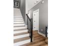 Stylish staircase featuring hardwood floors, white risers, and a sleek black railing at 3484 Orchard St, Atlanta, GA 30354