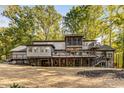 Expansive rear exterior featuring multiple balconies, a stone foundation, and a sprawling yard at 8316 Hewlett Rd, Sandy Springs, GA 30350