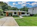 Lovely white-brick home featuring a driveway, manicured lawn, mature trees, and stylish carport at 4237 Rickenbacker Ne Way, Atlanta, GA 30342
