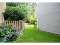 Backyard featuring a well-maintained lawn, a wooden fence, mature trees, and blooming hydrangeas at 3053 Shadow Walk Ln, Tucker, GA 30084