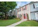 Inviting townhome with a lush green lawn, mature trees, and an appealing red front door and shutters at 3053 Shadow Walk Ln, Tucker, GA 30084
