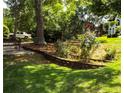 Picturesque backyard featuring mature trees, lush green grass, and terraced flower beds at 10815 Tuxford Dr, Alpharetta, GA 30022