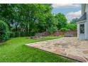 Backyard with stone patio, fire pit, and hot tub; lush greenery and privacy fence at 10980 Pinehigh Dr, Alpharetta, GA 30022