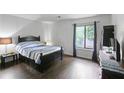 Well-lit bedroom featuring dark furniture, wood floors, and a large window at 1271 Muirforest Ln, Stone Mountain, GA 30088