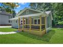 A cozy home showcasing a covered porch with dark railings and an inviting green lawn surrounded by green trees and a blue sky at 1675 White Oak Way, Decatur, GA 30032