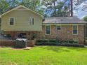 Spacious backyard featuring a brick patio, lush green grass, mature trees, and brick exterior of the house at 4094 Carlisle Pl, Stone Mountain, GA 30083