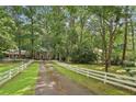 A picturesque view features a red brick home with a white picket fence and tree lined driveway at 980 Hightower Trl, Sandy Springs, GA 30350