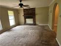 A traditional-style living room featuring a brick fireplace, a ceiling fan, carpet and an arched doorway at 718 Hardy Way, Hiram, GA 30141