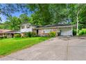 Exterior view of a house with mature trees, a carport, and a spacious driveway at 6250 Graceland Cir, Morrow, GA 30260