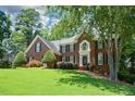 Charming two-story brick home with manicured lawn, mature trees, and inviting front entrance at 1464 Chatsworth Trace, Lawrenceville, GA 30044