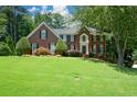 Charming two-story brick home with manicured lawn, mature trees, and inviting front entrance at 1464 Chatsworth Trace, Lawrenceville, GA 30044