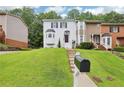 View of the front of the townhome with a large lawn, manicured greenery, and a classic white painted brick facade at 208 Hembree Park Ter, Roswell, GA 30076