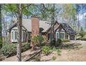 Brick home nestled among mature trees with a chimney, bay windows, and a two-car garage at 2689 Spring Rock Ne Ct, Roswell, GA 30075