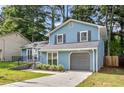 Charming two-story home with light blue siding, gray shutters, attached garage, and well-maintained front lawn at 6176 Hyde Park Ln, Lithonia, GA 30058