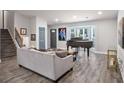 Spacious living room showcasing a modern gray couch, piano, staircase, and large windows at 6176 Hyde Park Ln, Lithonia, GA 30058