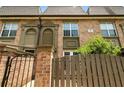 A brick townhouse displaying covered entryways, a fenced patio, and trimmed landscaping at 6980 Roswell Rd # P6, Atlanta, GA 30328