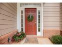 Close-up of a welcoming front door with sidelights, a wreath, and colorful potted flowers at 2427 Camata, Marietta, GA 30066