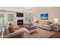 Bright living room with a fireplace, plush sofas, hardwood floors, and large windows that fill the space with natural light at 555 Sydney Crest Ln, Lawrenceville, GA 30046