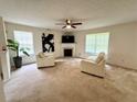 Bright living room featuring neutral walls, carpet, a fireplace, and comfortable seating for relaxing at 105 Avonwood Cir, Locust Grove, GA 30248