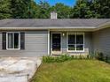 Close up of the home’s entrance with a black door, manicured landscaping, and gray siding at 30 Court S, Ellenwood, GA 30294