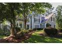 Two-story home featuring manicured landscaping on a sloped front lawn with mature trees at 4030 Greatwood Path, Alpharetta, GA 30005