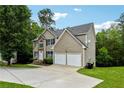 Two-story home with a two-car garage, stone accents, lush landscaping, and a curved driveway at 4240 N Braves Cir, Douglasville, GA 30135