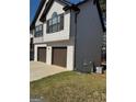 Side view of a two-story house with a two-car garage and air conditioning unit at 955 Loch Forest Way, Riverdale, GA 30296