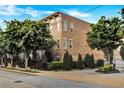 Brick corner lot townhouse building surrounded by mature, lush trees, shrubs, and manicured lawns at 326 Brownstones Ne Cir, Atlanta, GA 30312