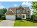 Charming two-story brick home with a lush green lawn and beautiful landscaping at 773 Van Briggle Path, Sugar Hill, GA 30518