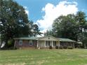 Inviting single-story brick home featuring a green metal roof, manicured lawn, and mature trees at 1253 Gatewood Drive Dr, Lawrenceville, GA 30043