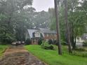 View of a brick two-story home with a black fence, lush greenery, and a driveway from the street at 423 Orchards Walk, Stone Mountain, GA 30087