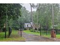 View of a brick two-story home with a black fence, lush greenery, and driveway from the road at 423 Orchards Walk, Stone Mountain, GA 30087