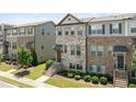 Charming townhome showcasing a mix of brick and stone, a covered porch, and professional landscaping at 4458 Dunblane Ave, Sugar Hill, GA 30518