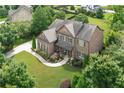 An aerial view of the brick home showcasing its landscaping, driveway, and lush green surroundings at 4547 Meadow Green Nw Ln, Acworth, GA 30101