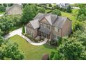 Stunning aerial view of brick two-story home surrounded by lush greenery and a long driveway at 4547 Meadow Green Nw Ln, Acworth, GA 30101