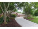 A long driveway leads to the brick home, framed by mature trees, green lawn, and manicured landscaping at 11940 Wexford Club Dr, Roswell, GA 30075