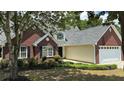 Lovely brick home showcasing a well-maintained lawn, mature trees, and a two-car garage at 3066 Gem Creek Rd, Buford, GA 30519